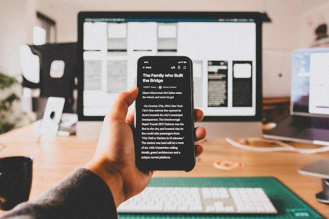 Two business professionals review stock market data on a smartphone and laptop in a contemporary office environment.