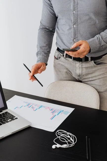 A contemporary workspace where hands review marketing data on a laptop alongside printed documents.